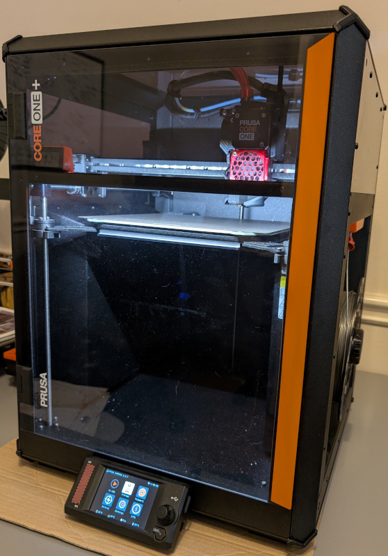 Prusa CORE One+ months after initial kit assembly. Sitting on sheet of cardboard on project table.